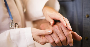 Rheumatoid Arthritis Meets Precision Medicine Caring female doctor helping senior male patient. She checks his hands for arthritis, aids him in walking, or just consoles him. Close up of hands. Unrecognizable people. Nursing home/assisted living, home or clinic setting.
