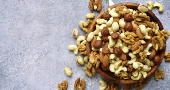 Nut Consumption Linked to Increased Colon Cancer Survival Assortment of nuts in a wooden bowl on a light slate or stone background - healthy snack.Top view with copy space.