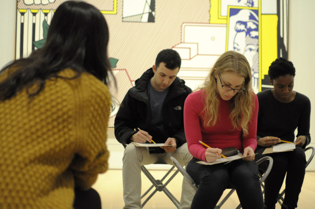 In one exercise, students sit with their backs to a painting and sketch what they think the painting looks like while listening to a peer describe the work.