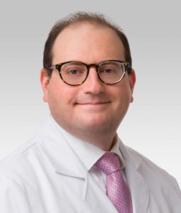 Seth Pollack, MD, the Steven T. Rosen, MD, Professor of Cancer Biology, posing for a headshot and wearing a white coat and pink tie. 