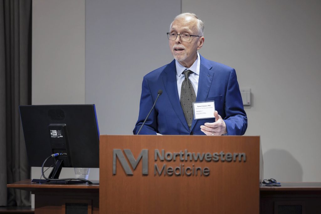 Robert Vassar, PhD, stands behind a podium and addresses attendees.