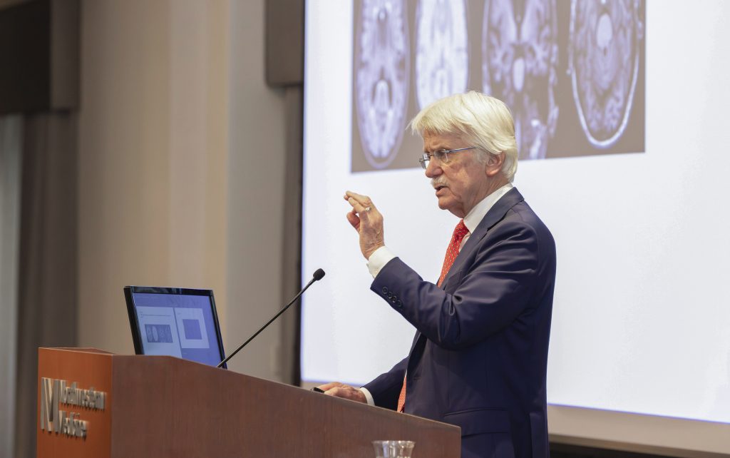 Ronald C. Petersen, MD, PhD, speaks at a podium as he delivers the keynote lecture.